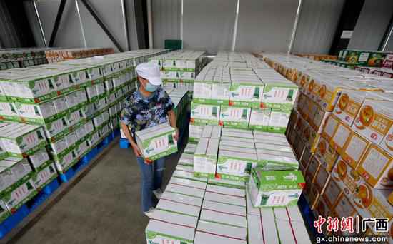 在广西融安县农产物加工暨粤桂扶贫协作财富园一家饮料出产企业的扶贫车间,工人在搬运产物。覃庆和 摄 广西融安粤桂扶贫财富园区企业出产忙