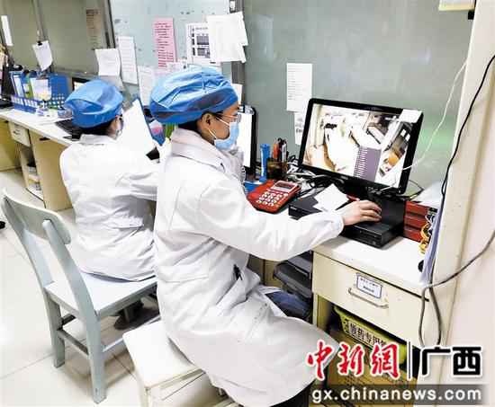 麻芝英(右一)通过视频监控查察病房内新冠肺炎患者状况。 抗疫“最美家庭”柳州市4个家庭获全国、自治区表扬