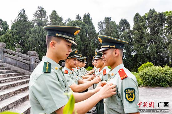 在团旗的见证下,党员及老团员代表为新团员佩戴团徽。武警玉林支队陆川中队供图 武警玉林支队陆川中队开展主题团日活动